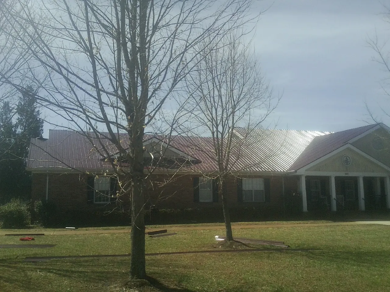 Red metal roof on a brick building seen from the front lawn in Lowry City