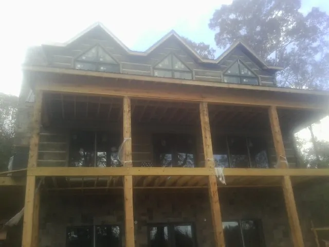 Dormers and porch framing on a large log home under construction — Roof Coating work by our crew in Lowry City