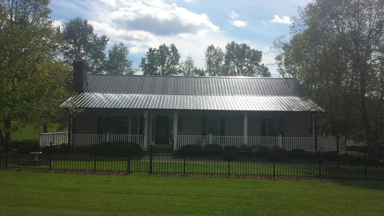 Gray metal roof on a brick ranch with a full width front porch — Gutter Guard Installation work by our crew in Lowry City