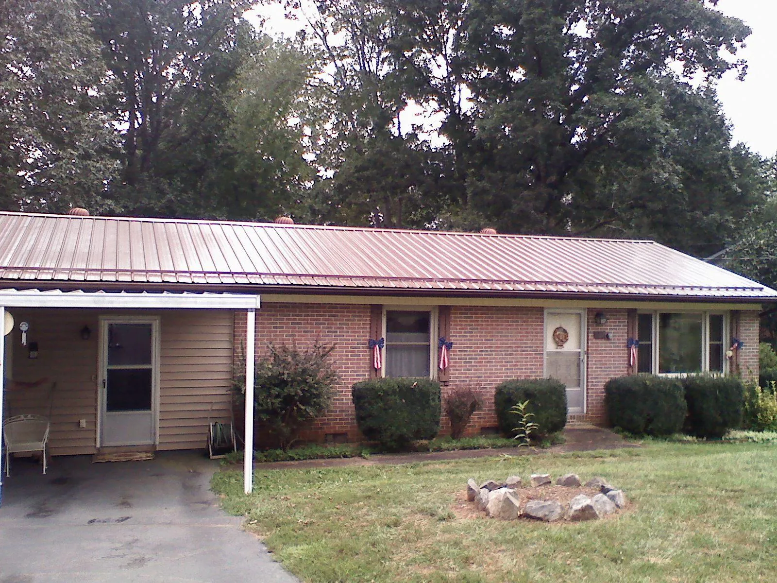 Bronze metal roof and carport on a brick ranch home — Roof Repair work by our crew in Lowry City