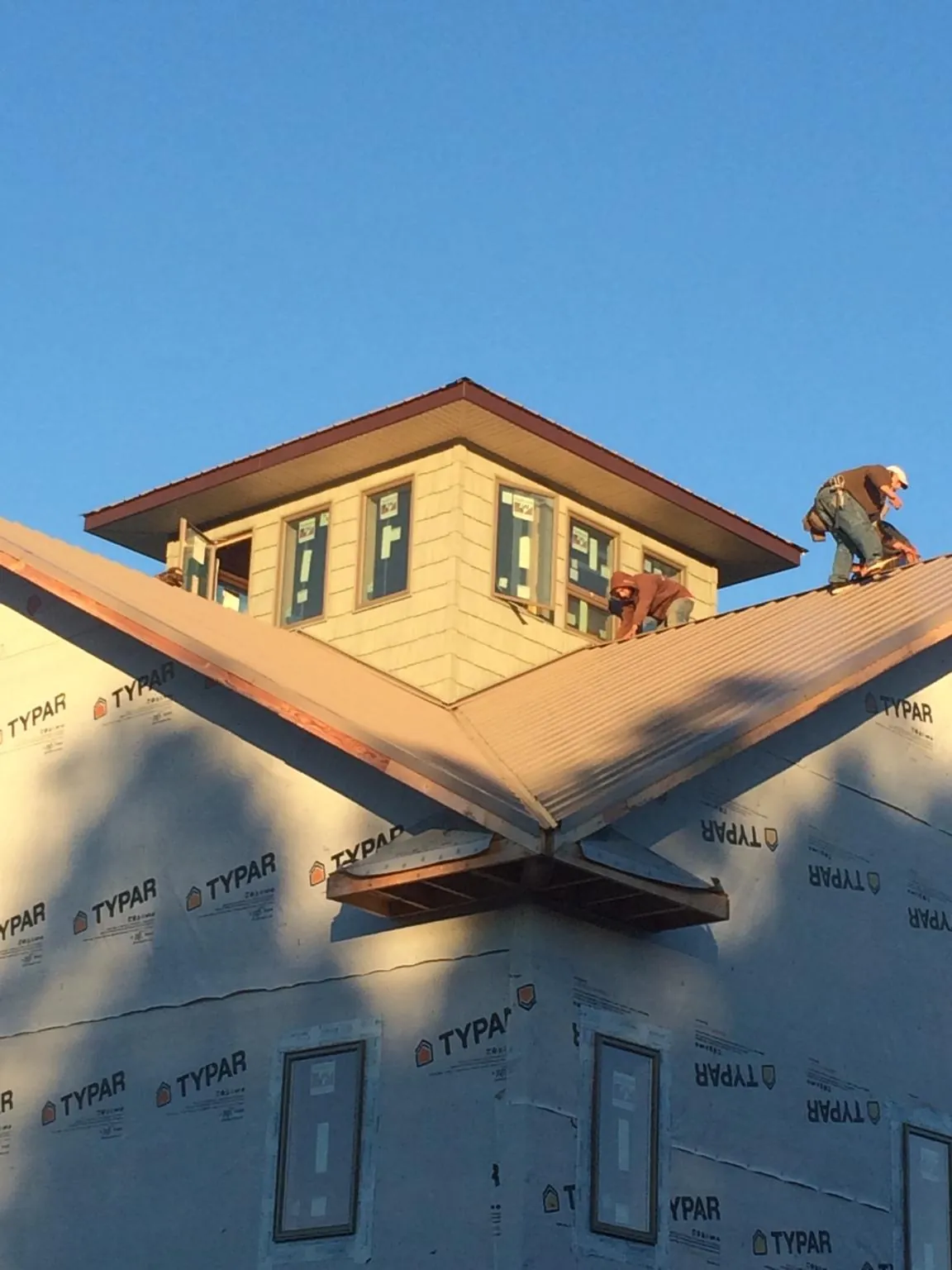 Roofers working around a rooftop cupola on a new metal roof at sunset — Roof Waterproofing in Lowry City by Roofing Brothers